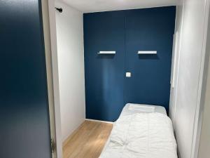 Cette petite chambre comprend un lit et un mur bleu. dans l'établissement Mobil Home 4 / 6 personnes, à Nances