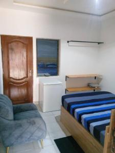 1 dormitorio con 1 cama, 1 silla y 1 ventana en Kondjikpé, en Cotonou