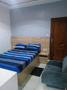 Un dormitorio con una cama con almohadas azules y una silla en Kondjikpé, en Cotonou