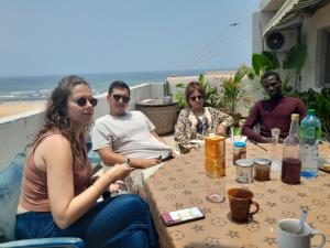 a group of people sitting at a table near the beach at Casa Djoko in Dakar