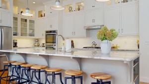 a kitchen with white cabinets and a large island with stools at Lamb Haven in South Haven