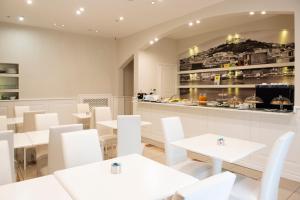 ein Restaurant mit weißen Tischen und weißen Stühlen in der Unterkunft Certosa Suite in Neapel