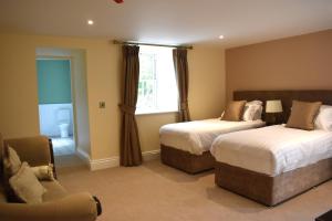 1 dormitorio con 2 camas, silla y ventana en Tobervilla Guest House, en Caherdaniel