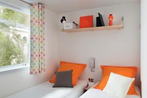 a bedroom with orange and white pillows and a window at Camping Le Perpetuum in Domme +19 photos