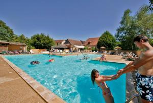 a man and a woman in a swimming pool at Camping Le Perpetuum in Domme