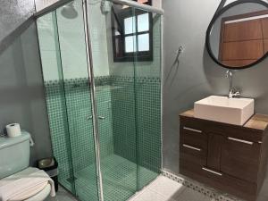 uma casa de banho com uma cabina de duche em vidro e um lavatório. em Chalé 08 com hidro no coração de Penedo em Itatiaia