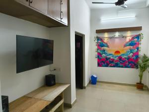 sala de estar con TV de pantalla plana en la pared en Calcutta Backpackers en Calcuta