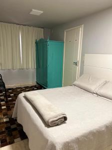 a bedroom with a white bed and a blue cabinet at Norte Hospedagem in Lages