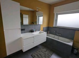 bagno con lavandino, vasca e specchio di Tweepersoonskamer centrum Poperinge a Poperinge