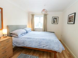 een slaapkamer met een bed met een blauw dekbed en een raam bij Paws-A-While in Norwich