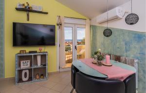 ein Esszimmer mit einem TV und einem Tisch mit Stühlen in der Unterkunft Cozy Apartment In Kastel Stari With Kitchen in Kaštela