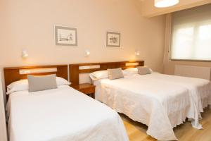 two beds in a room with white sheets at Hotel Ros Mary in Ribadeo