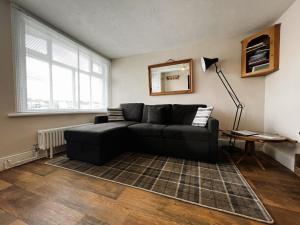 uma sala de estar com um sofá preto e um espelho em Bell Cottage em Cowes