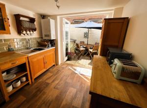 uma cozinha com um lavatório e uma mesa com um guarda-chuva em Bell Cottage em Cowes