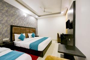 ニューデリーにあるBalwood Suites Near Delhi Airportのベッド2台とテレビが備わるホテルルームです。