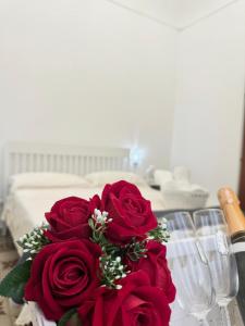 a bouquet of red roses on a table with wine glasses at Il gufo barocco in Noto