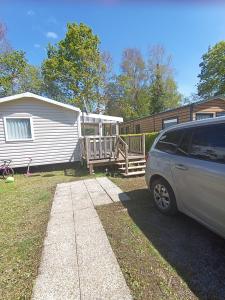 Un coche aparcado delante de una casa y una caravana. en mobil home 3 chambres 152, en Pont-Aven