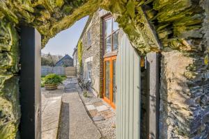 an old stone house with an orange door on a street at Polean Farm Old Farmhouse - With Large Jacuzzi, Games Room, Near the Sea and with Free Access to a Nearby Pool in Looe