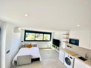 a white bedroom with a bed and a window at Pandi's Place in Sant Pere de Ribes