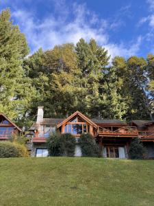 a large house with trees in the background at El Remanso del Lago in Villa La Angostura +41 photos