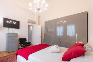 a bedroom with a bed with red pillows and a chandelier at Chic Elegance at Borgo Tommasini Apartment in Parma