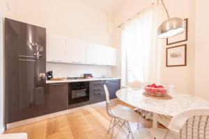 a kitchen with a table with a bowl of fruit on it at Chic Elegance at Borgo Tommasini Apartment in Parma
