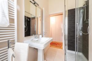 a white bathroom with a sink and a shower at Chic Elegance at Borgo Tommasini Apartment in Parma +9 photos