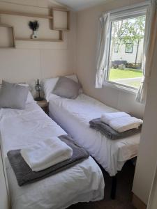 two beds in a small room with a window at Luxury Hot Tub Caravan Tattershall in Tattershall
