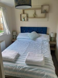 uma cama azul com duas toalhas brancas em Luxury Hot Tub Caravan Tattershall em Tattershall