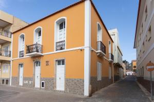 a yellow building with white doors and a street at O Sobrado Mariazinha & Inácio Lima in Praia