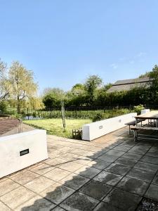a patio with white benches and a field at Oak Grange holiday cottage in Hoxne