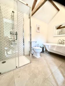 a bathroom with a shower and a tub and a toilet at Oak Grange holiday cottage in Hoxne