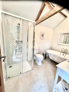 a bathroom with a shower and a tub and a toilet at Oak Grange holiday cottage in Hoxne