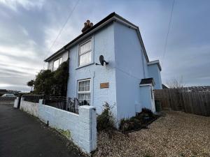 Una casa blanca con dos personas sentadas encima. en Kema Cottage, en East Cowes