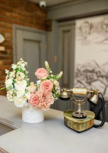 um telefone e um vaso de flores sobre uma mesa em Nota Bene Hotel & Restaurant em Lviv