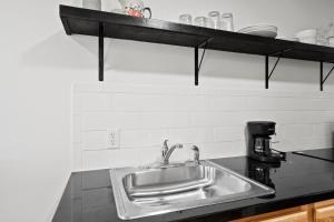 a kitchen counter with a sink and a shelf at Peach Street Super Suite in Medford