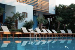 uma piscina com espreguiçadeiras ao lado de um prédio em Hotel Athina em Velipoja