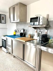 a kitchen with stainless steel counters and a microwave at Escondite central con terraza compartida en la azotea in Roses