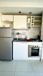 a kitchen with white cabinets and a stainless steel refrigerator at Luminoso departamento en Castelar centro p/2 pers in Castelar