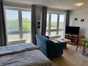 a bedroom with a blue chair and a television at Apartement Seeblick in Nordstrand