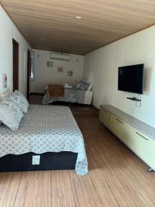 um quarto com uma cama e uma televisão de ecrã plano em Chalé 10 até 4 pessoas cozinha próx ao centro em Itatiaia