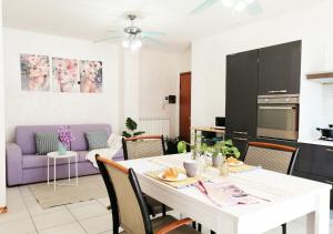 a kitchen and living room with a white table and purple couch at Holihome_C&C Sunrise House in Tortoreto Lido