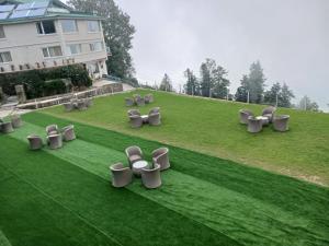 eine Gruppe von Stühlen auf einem Grasfeld in der Unterkunft Kufri Holiday Resort in Kūfrī