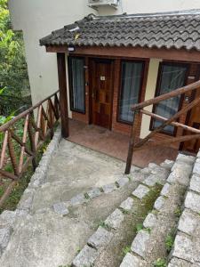 een klein huis met een veranda en een houten deur bij Chalé 10 até 4 pessoas cozinha próx ao centro in Itatiaia