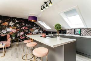 cocina con isla de cocina con taburetes rosados en The Glasgow Rose- Stylish Penthouse 2 Bed City Centre Apartment with Free Parking & Lift en Glasgow