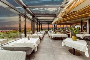 un ristorante con tavoli e sedie bianchi e finestre di Quellenhof Luxury Resort Lazise a Lazise