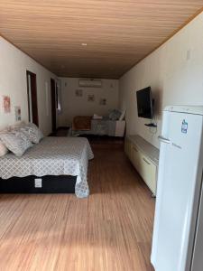 a bedroom with a bed and a refrigerator in it at Chalé 10 com cozinha próx ao centro in Itatiaia