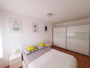 a white bedroom with a large white bed with yellow pillows at Apartment Felix in Rijeka