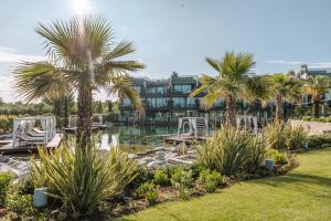 een resort met palmbomen en een waterlichaam bij Quellenhof Luxury Resort Lazise in Lazise