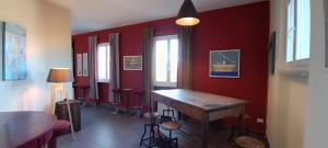 a room with red walls and a wooden table at Il Pescemagra HostelAmeglia in Ameglia